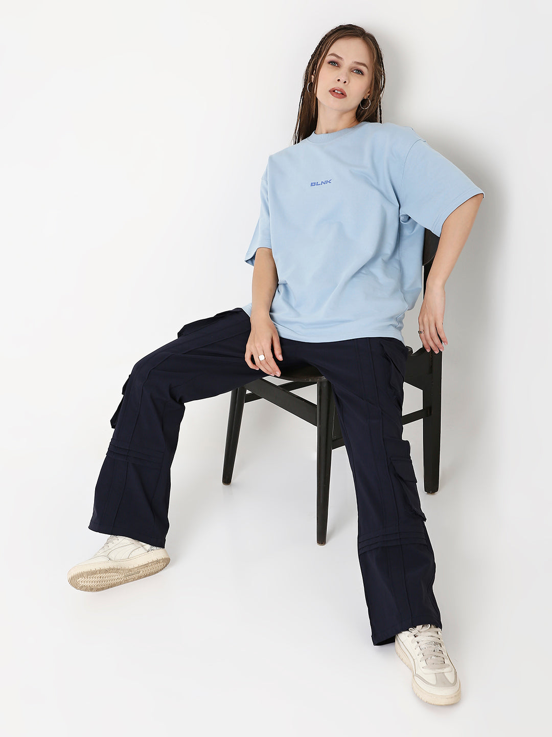 Light-blue oversized t-shirt with small printed text, paired with navy wide-leg pants and white sneakers.