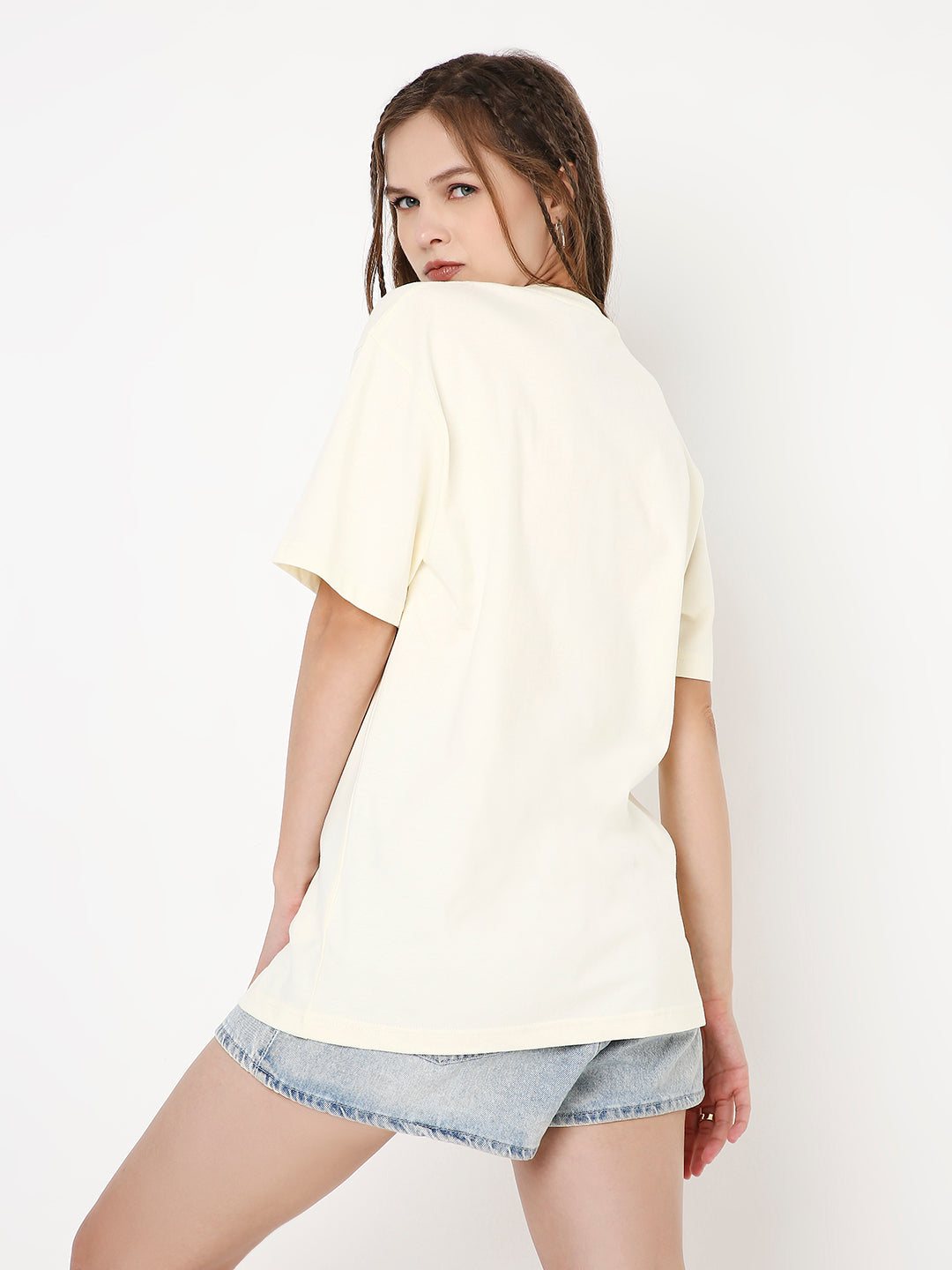 Off-white relaxed fit solid T-shirt with short sleeves worn with light denim shorts, back view.