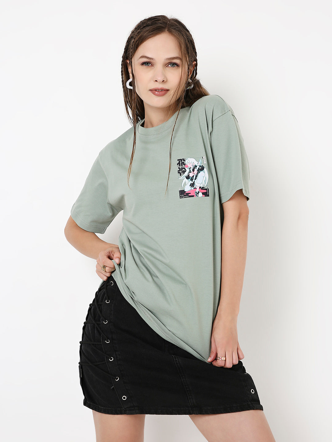 Sage green relaxed fit t-shirt with small black and white cow print pocket, worn with black buttoned skirt.