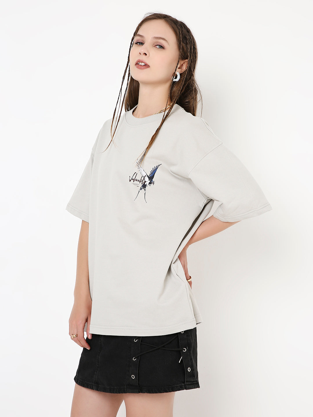 Oversized beige T-shirt with abstract skipping stone print on left chest, paired with black button-front skirt.