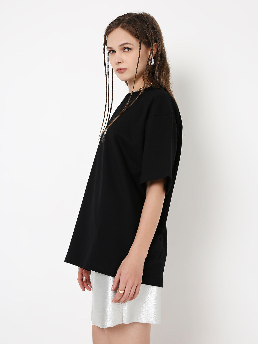 Oversize black T-shirt with loose fit and short sleeves styled with white shorts.