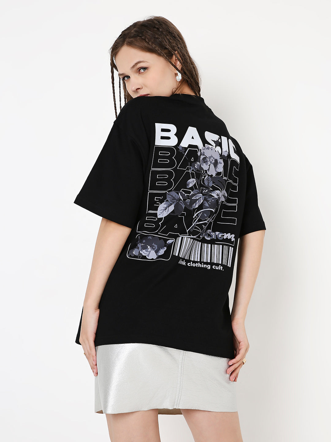 Oversize black T-shirt with bold white and gray graphic print on back, worn with white skirt.