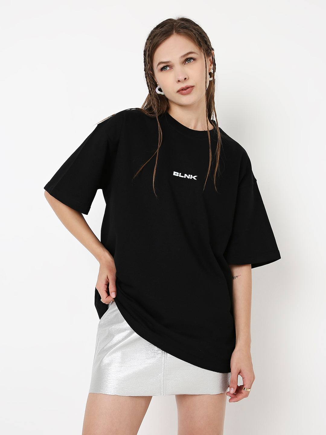 Oversize black t-shirt with small white "BLANK." print on chest, worn with silver skirt.