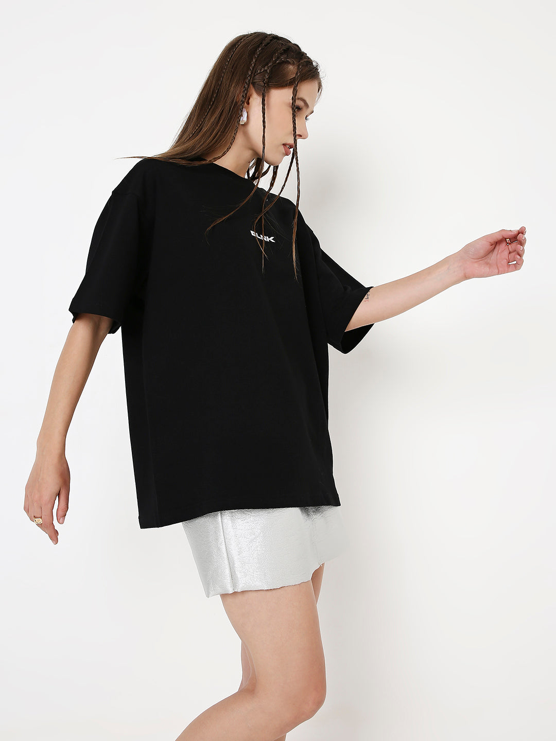 Oversize black T-shirt with small white graphic on chest, worn with white shorts.