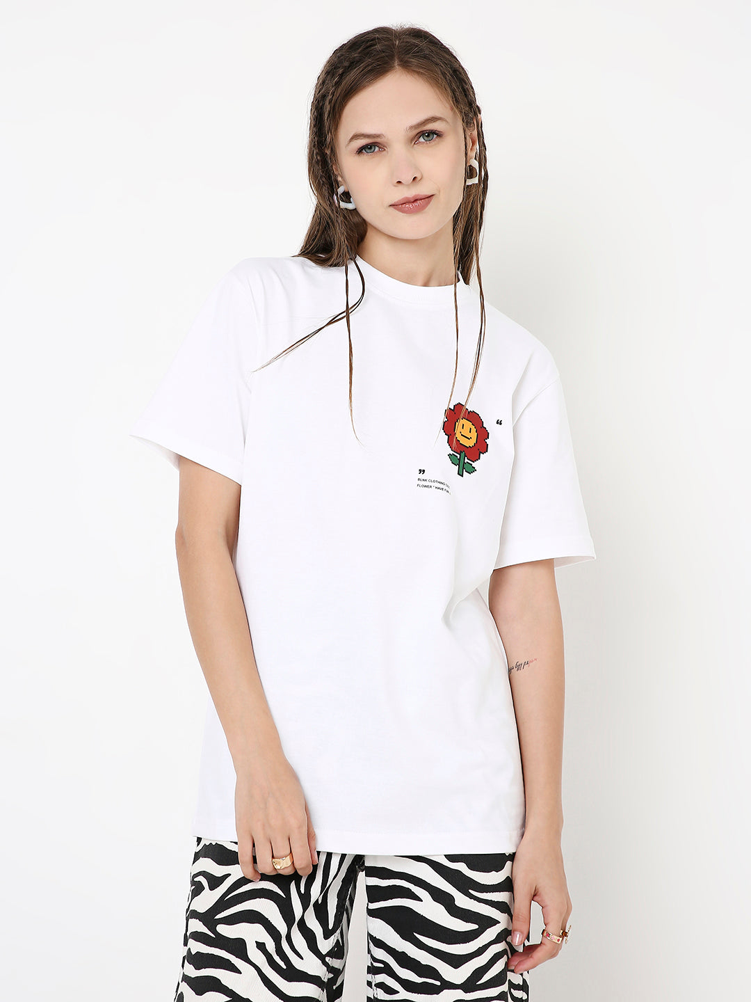 White relaxed fit t-shirt with small red rose and text print on left chest, worn with zebra print pants.