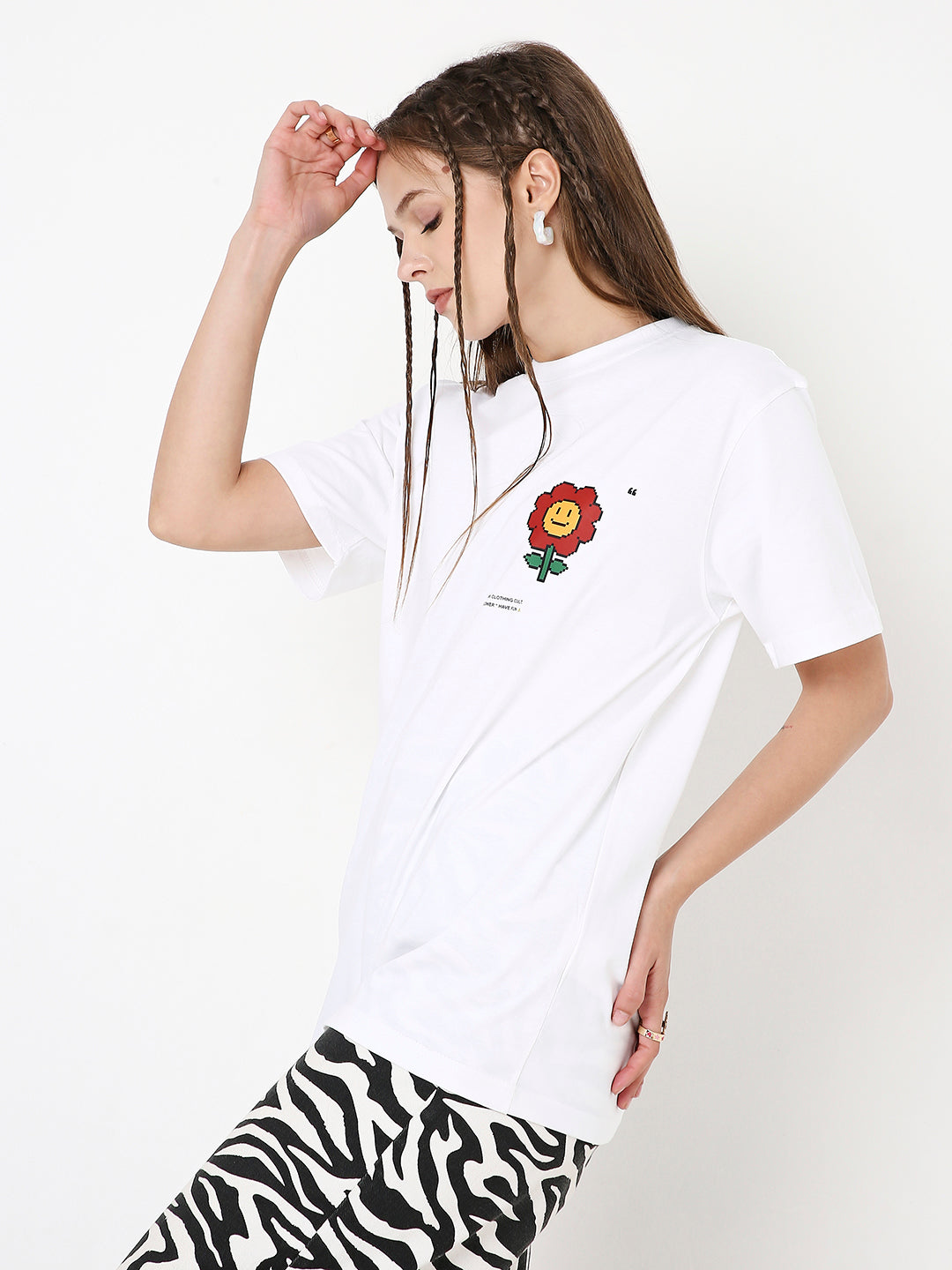 White relaxed fit t-shirt with small red and yellow flower graphic on chest, worn with zebra print pants.