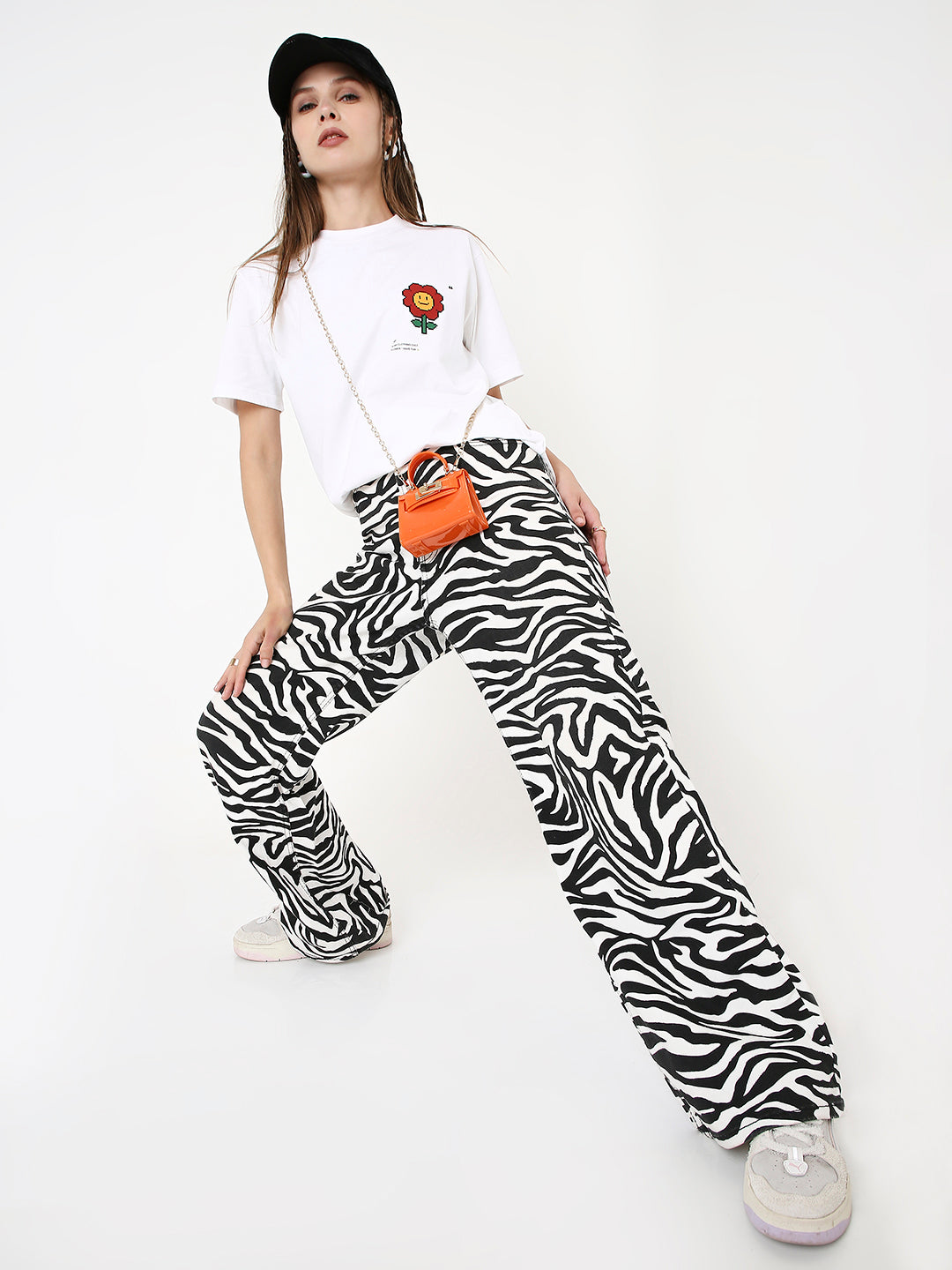 White relaxed fit T-shirt with small red flower print, paired with black and white zebra print pants and white sneakers.