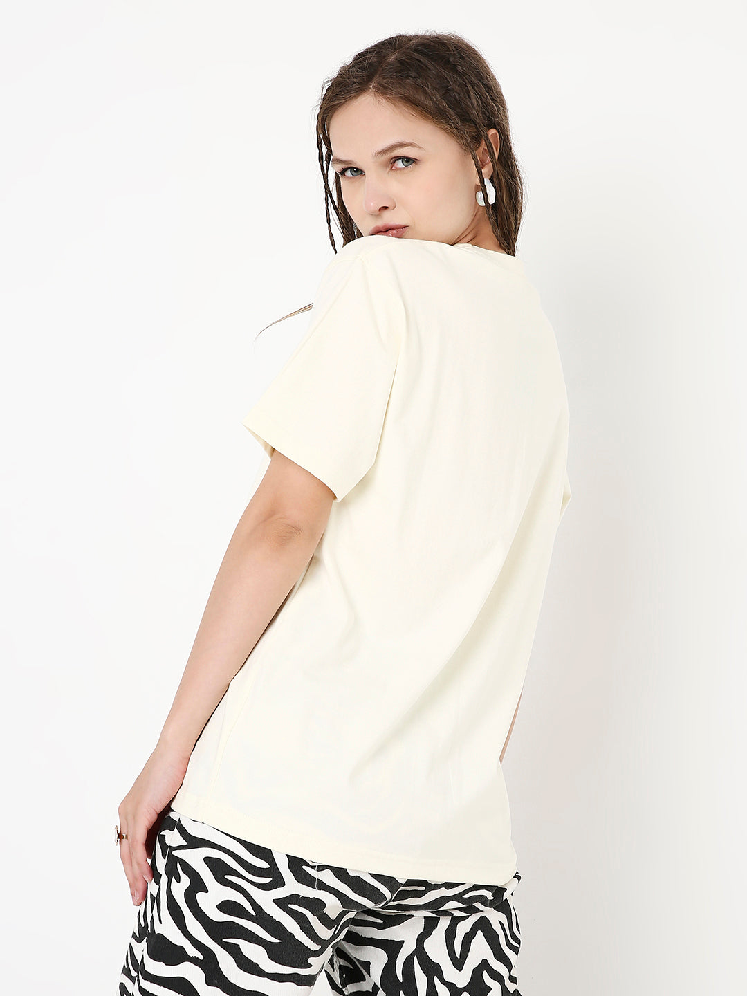 Relaxed fit off-white t-shirt paired with black and white abstract patterned pants, back view.