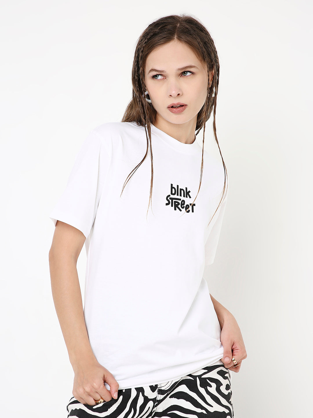White relaxed fit t-shirt with black "blink street" text print, worn with zebra print pants.