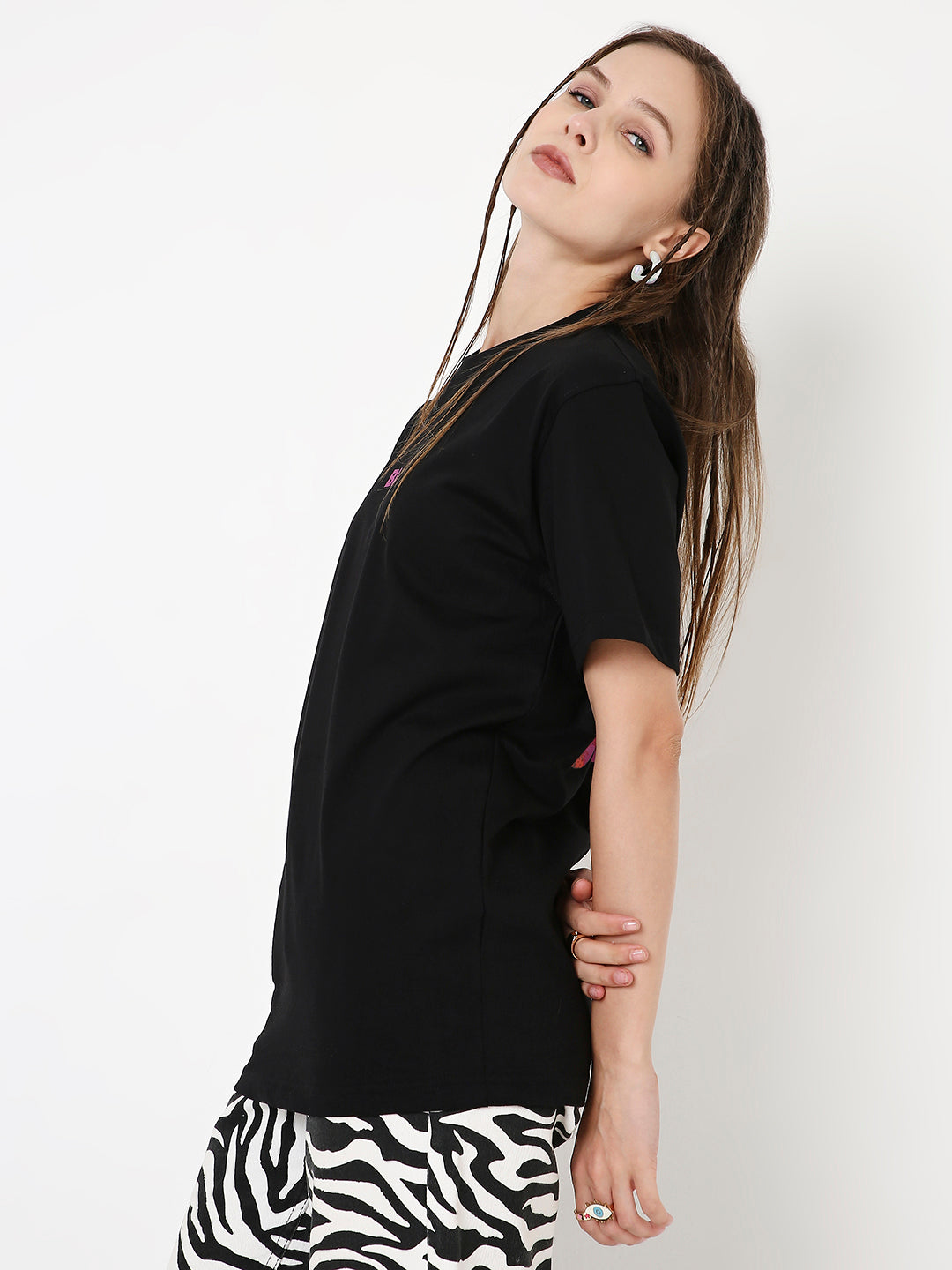 Black relaxed fit T-shirt paired with black and white zebra print pants on a woman against a white background.