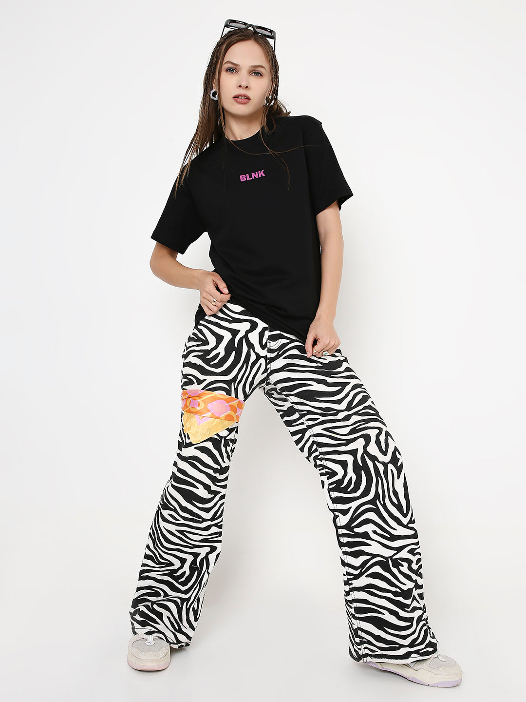 Black relaxed fit t-shirt with small pink logo on chest paired with zebra print wide-leg pants with colorful patches.