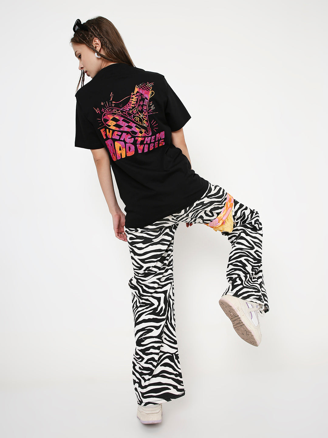 Black relaxed fit T-shirt with colorful graphic print on the back, paired with zebra print flared pants.