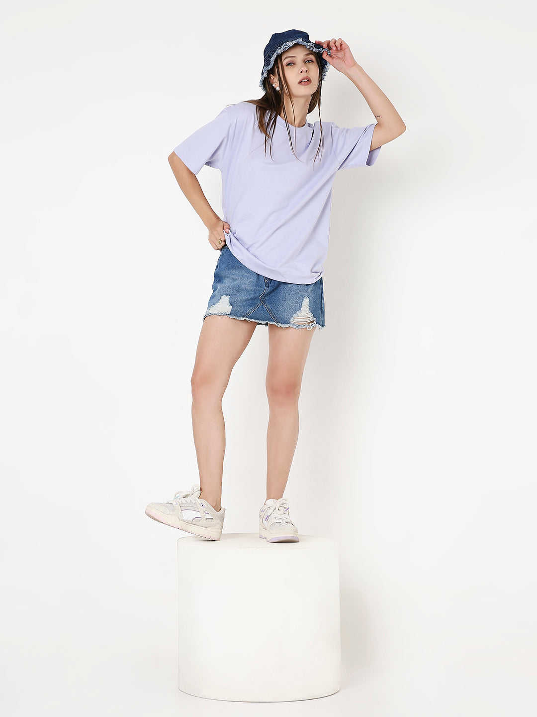 Relaxed fit lavender t-shirt with short sleeves paired with distressed denim mini skirt and white sneakers.