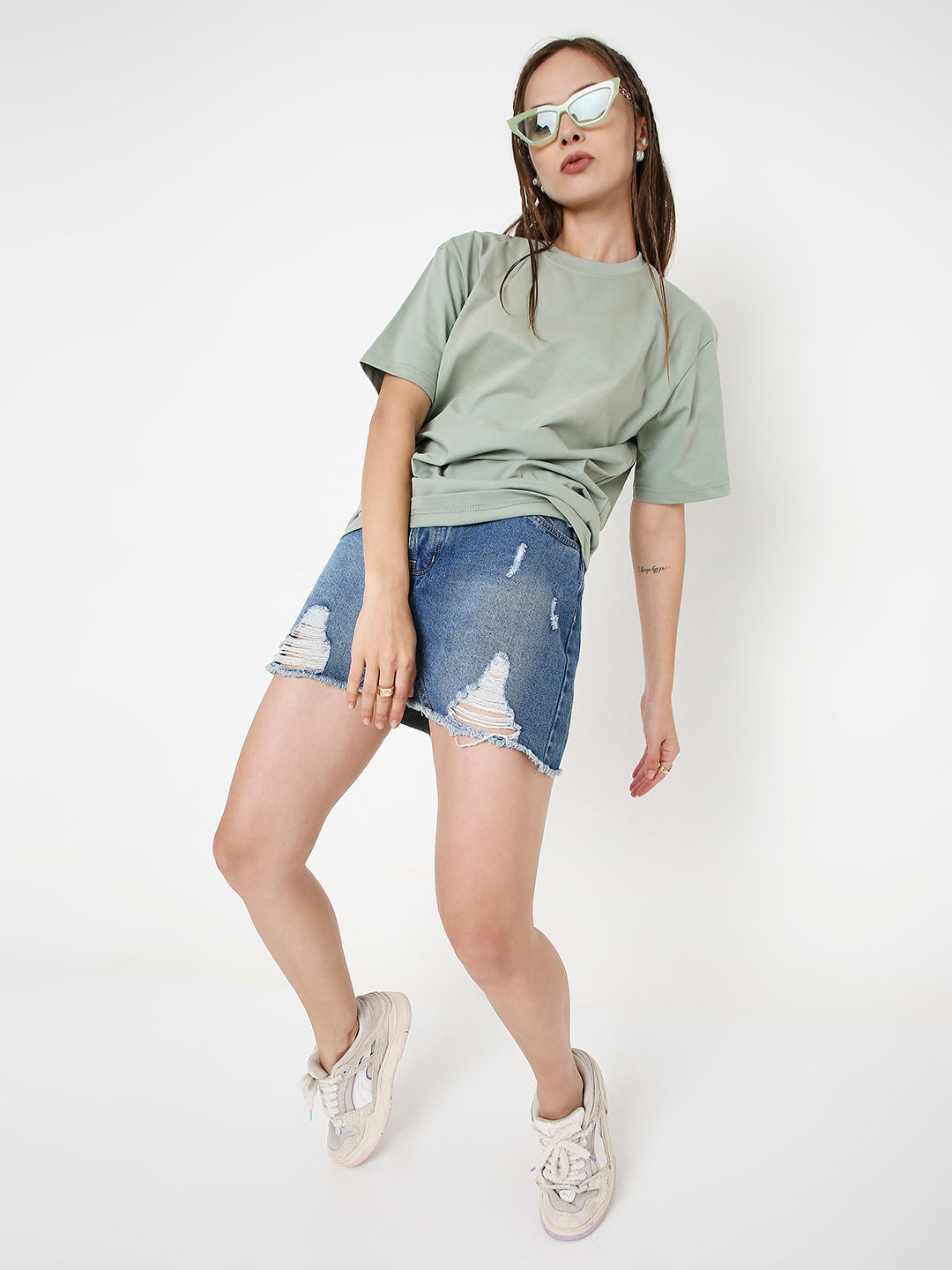 Relaxed fit sage green short-sleeve t-shirt paired with distressed denim shorts and white sneakers.