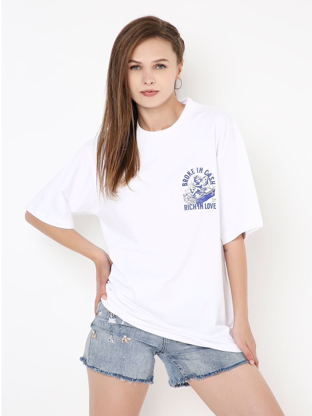 Oversize white T-shirt with blue graphic text on chest, paired with ripped denim shorts.