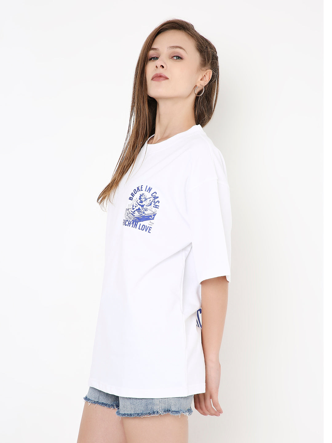 Oversize white t-shirt with blue graphic print on left chest, paired with denim shorts.