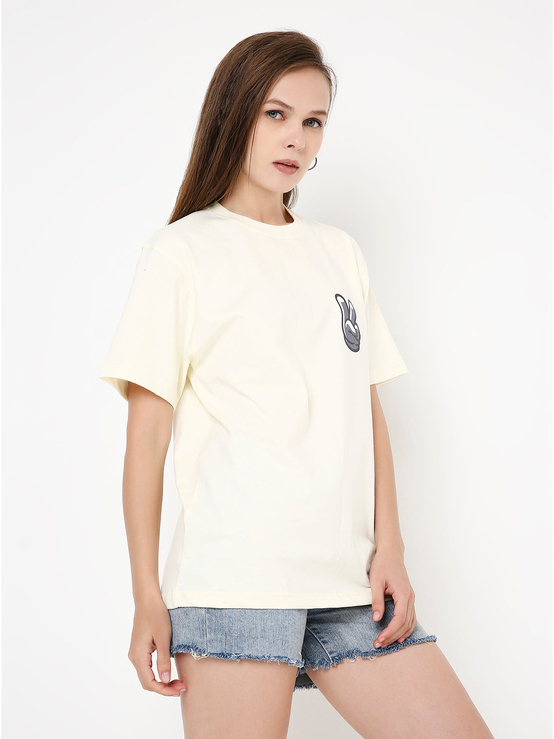 Off-white relaxed-fit t-shirt with small black graphic on left chest, worn with denim shorts.