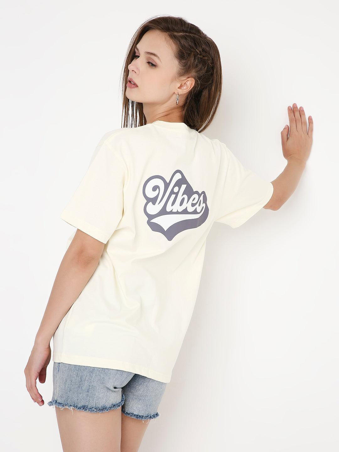 Off-white relaxed fit t-shirt with navy "Vibes" graphic print on the back, paired with denim shorts.