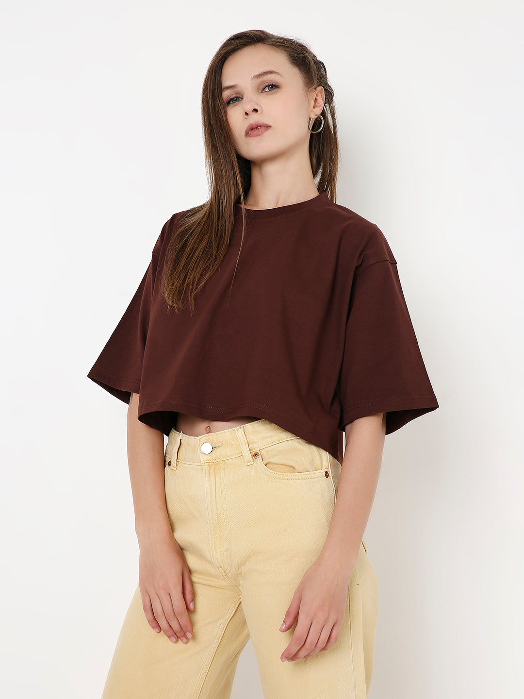 Oversize brown crop top with wide sleeves and round neck worn with beige high-waisted pants.