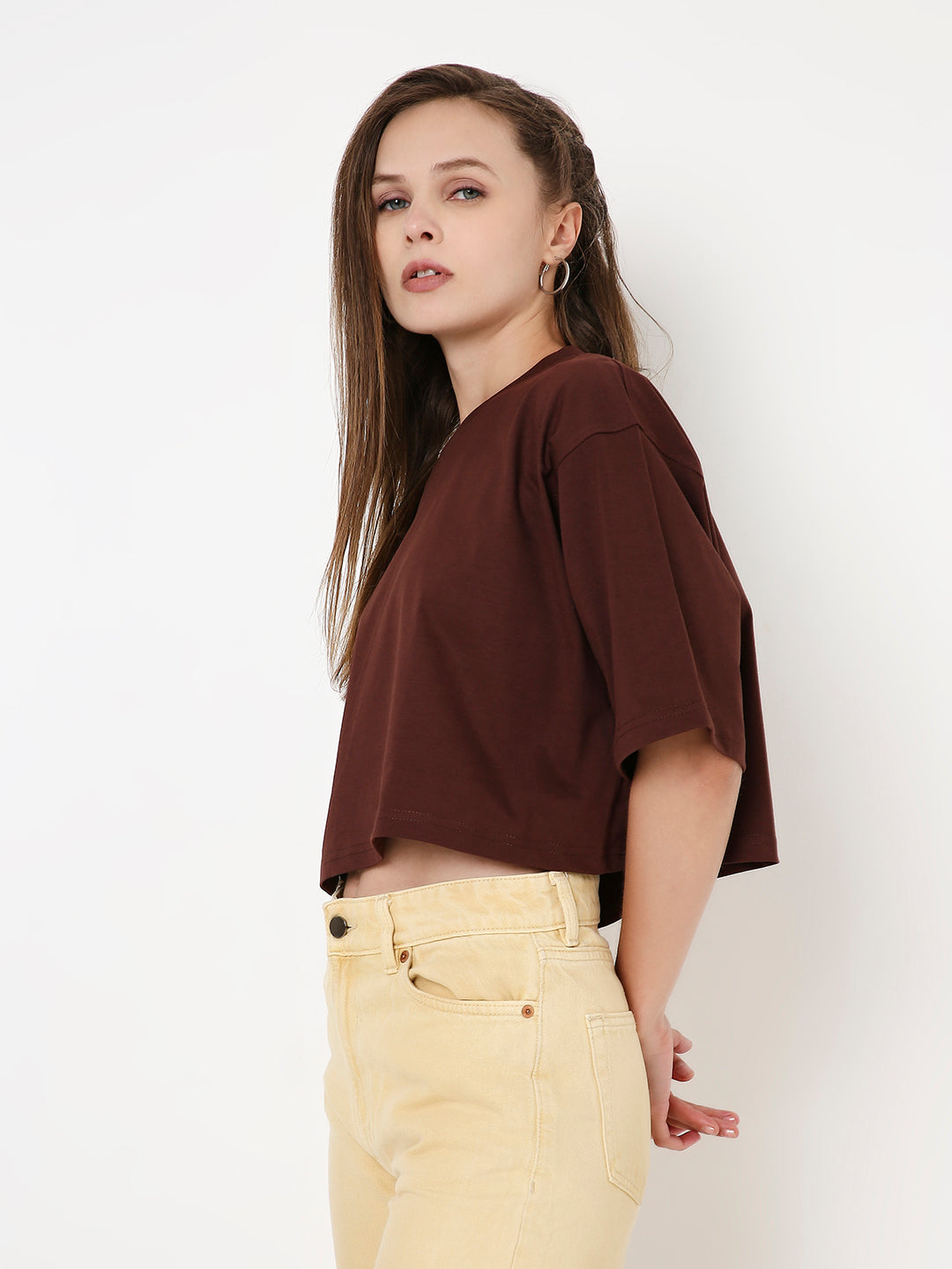 Oversize brown crop top with loose short sleeves and round neckline on model.