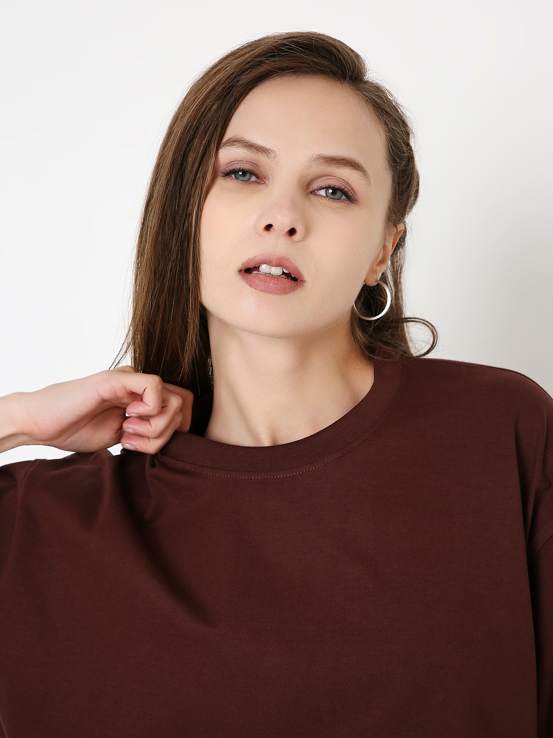 Oversize brown crop top with subtle dark print and crew neckline on model.