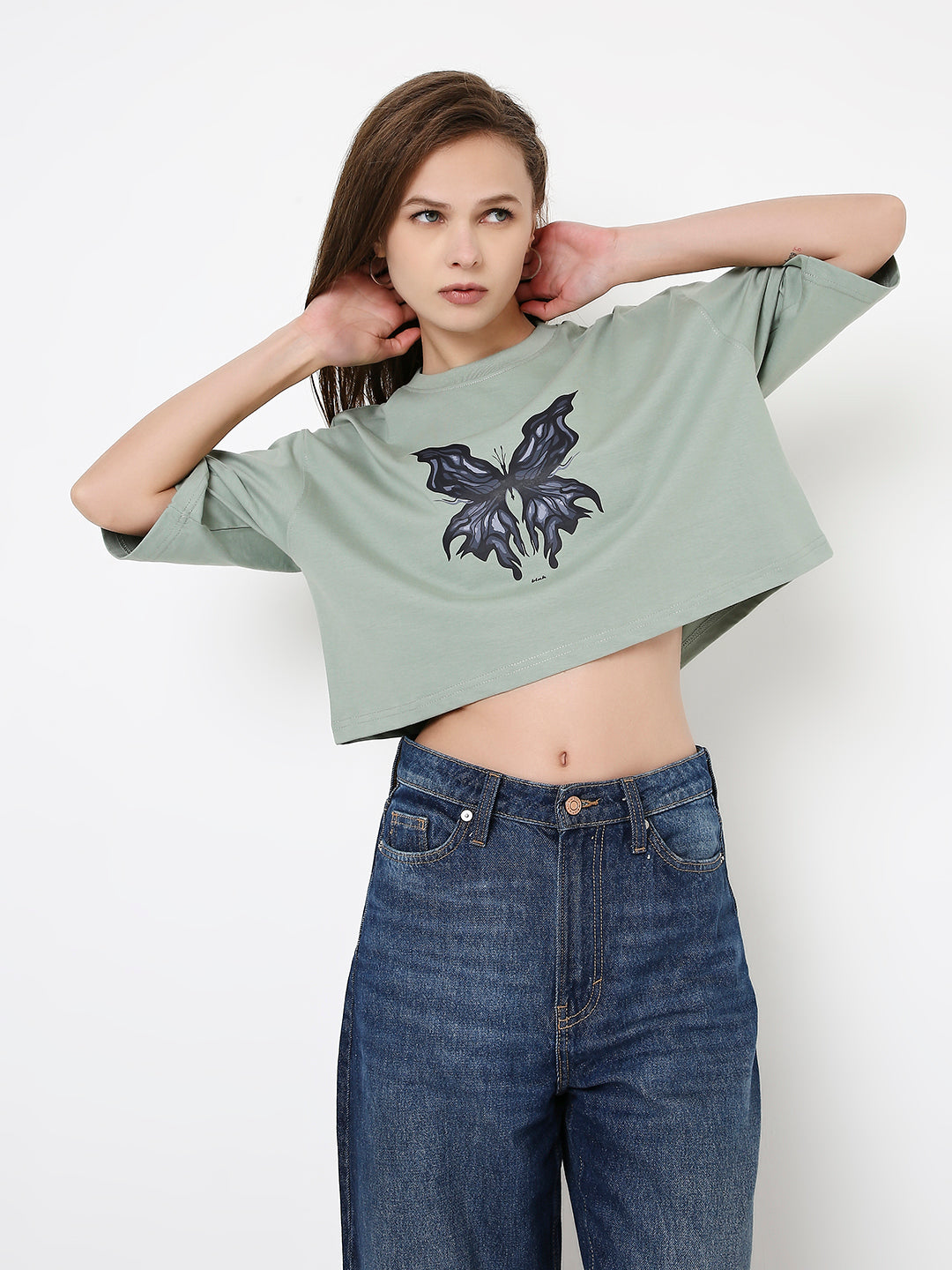 Oversize sage green crop top with black floral graphic and relaxed short sleeves.