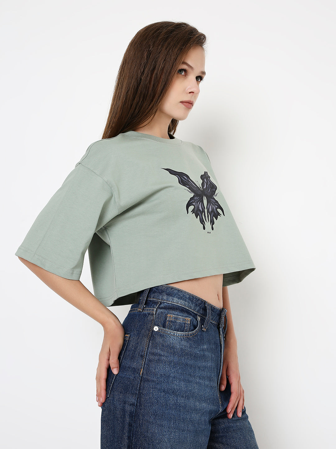 Oversize sage green crop top with black graphic print and wide short sleeves.