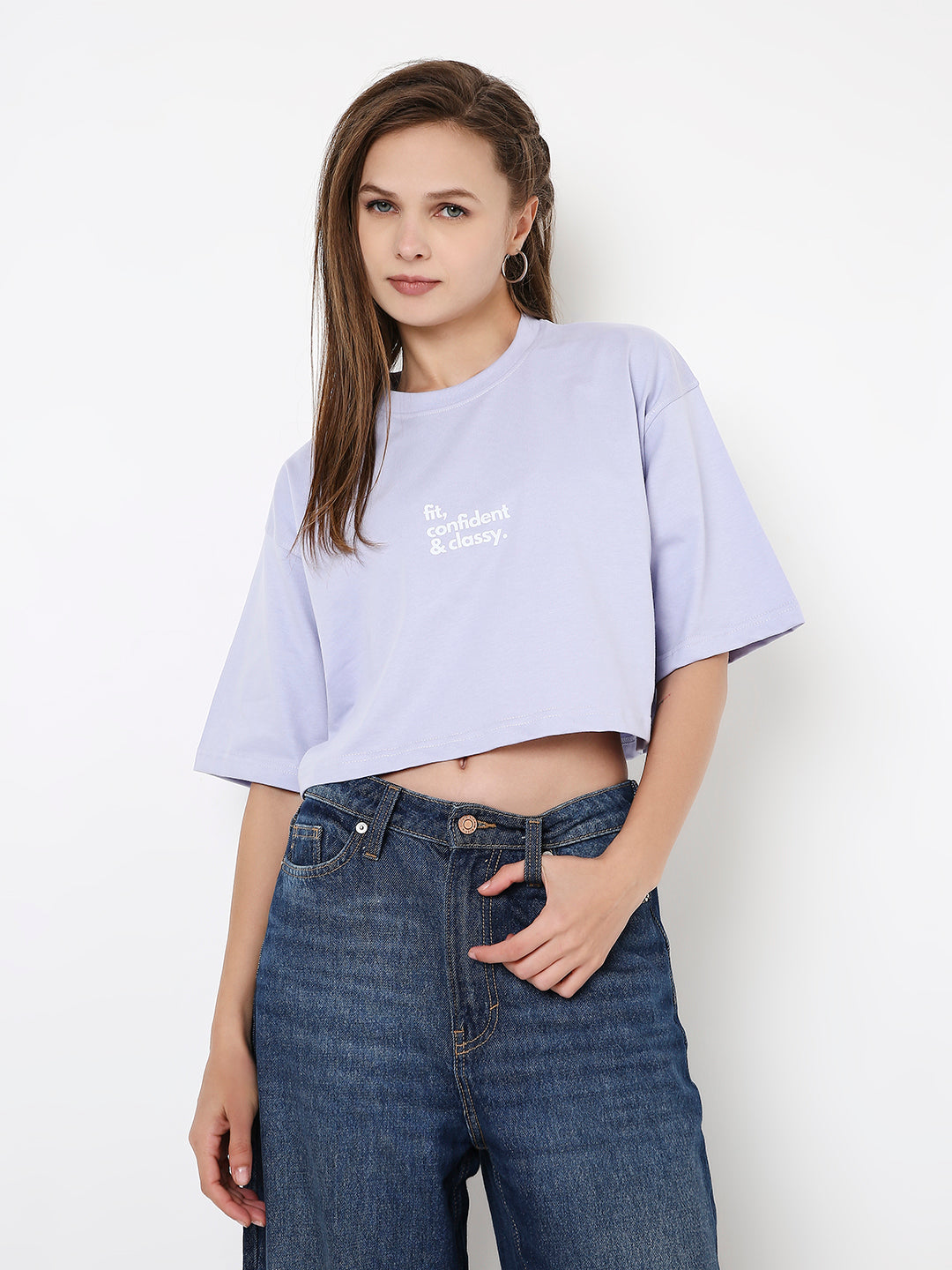 Lavender oversized crop top with white text print, paired with high-waisted blue jeans.