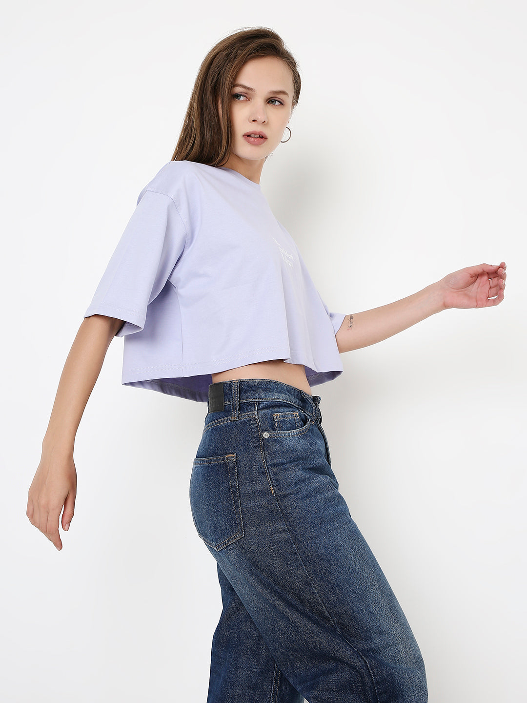 Lavender oversized crop top with short sleeves and a relaxed fit on model wearing dark blue jeans.