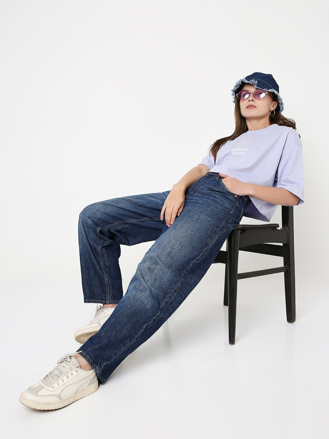 Oversize lavender crop top with subtle print, paired with relaxed dark blue jeans and white sneakers.