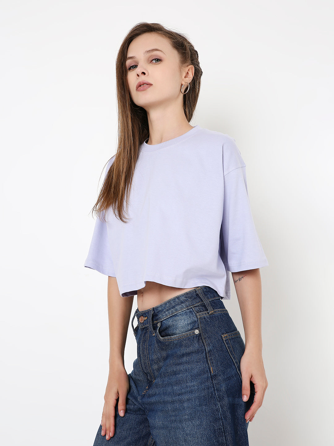 Lavender oversized crop top with short sleeves and crew neckline styled with high-waisted dark blue jeans.