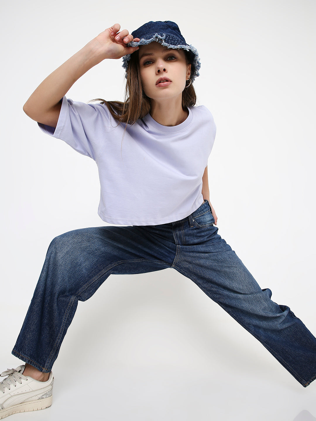 Lavender oversized crop top with subtle print, paired with wide-leg blue jeans and denim bucket hat.