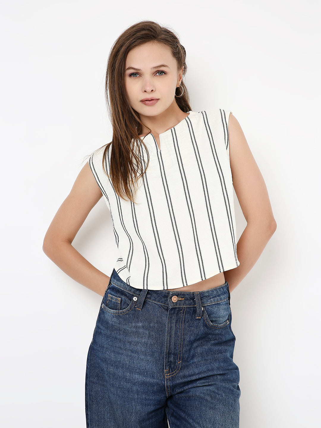 White sleeveless crop top with vertical black stripes, paired with high-waisted blue jeans.