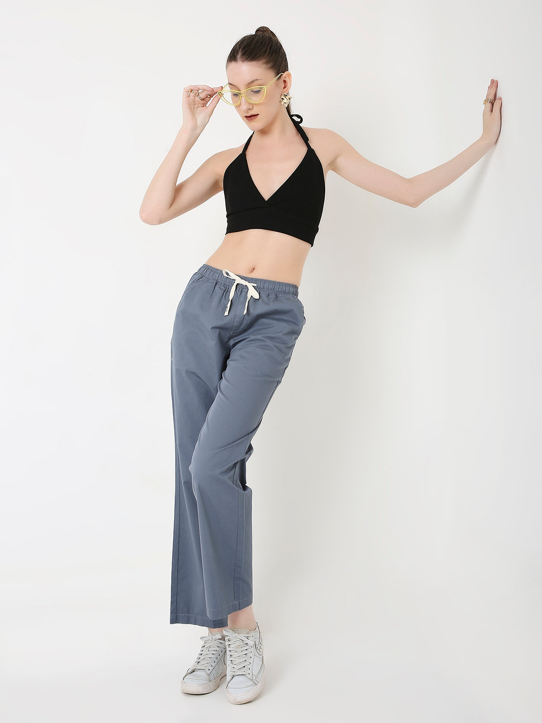 A model wearing slate blue relaxed fit drawstring pants with an adjustable waistband and a black crop top.