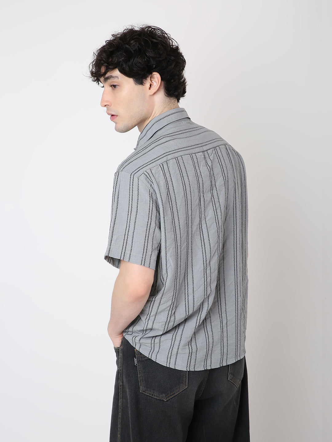 Man wearing a gray striped shirt against a plain background