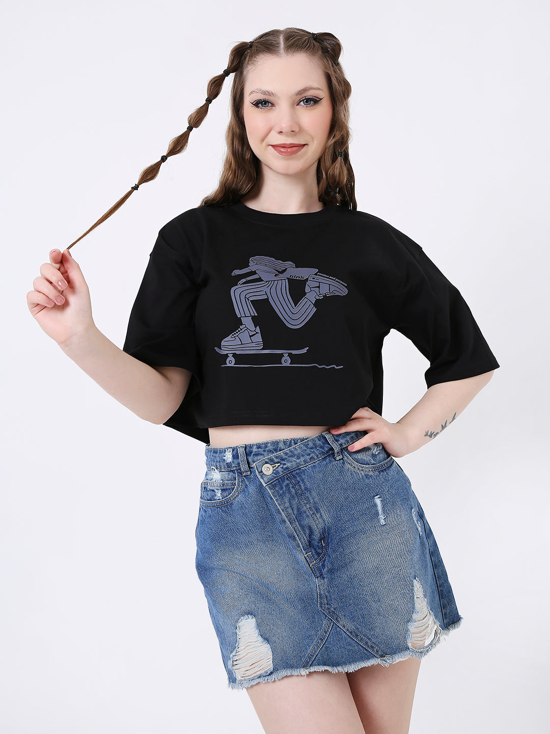 Black oversized crop top with graphic print, worn with distressed denim mini skirt.