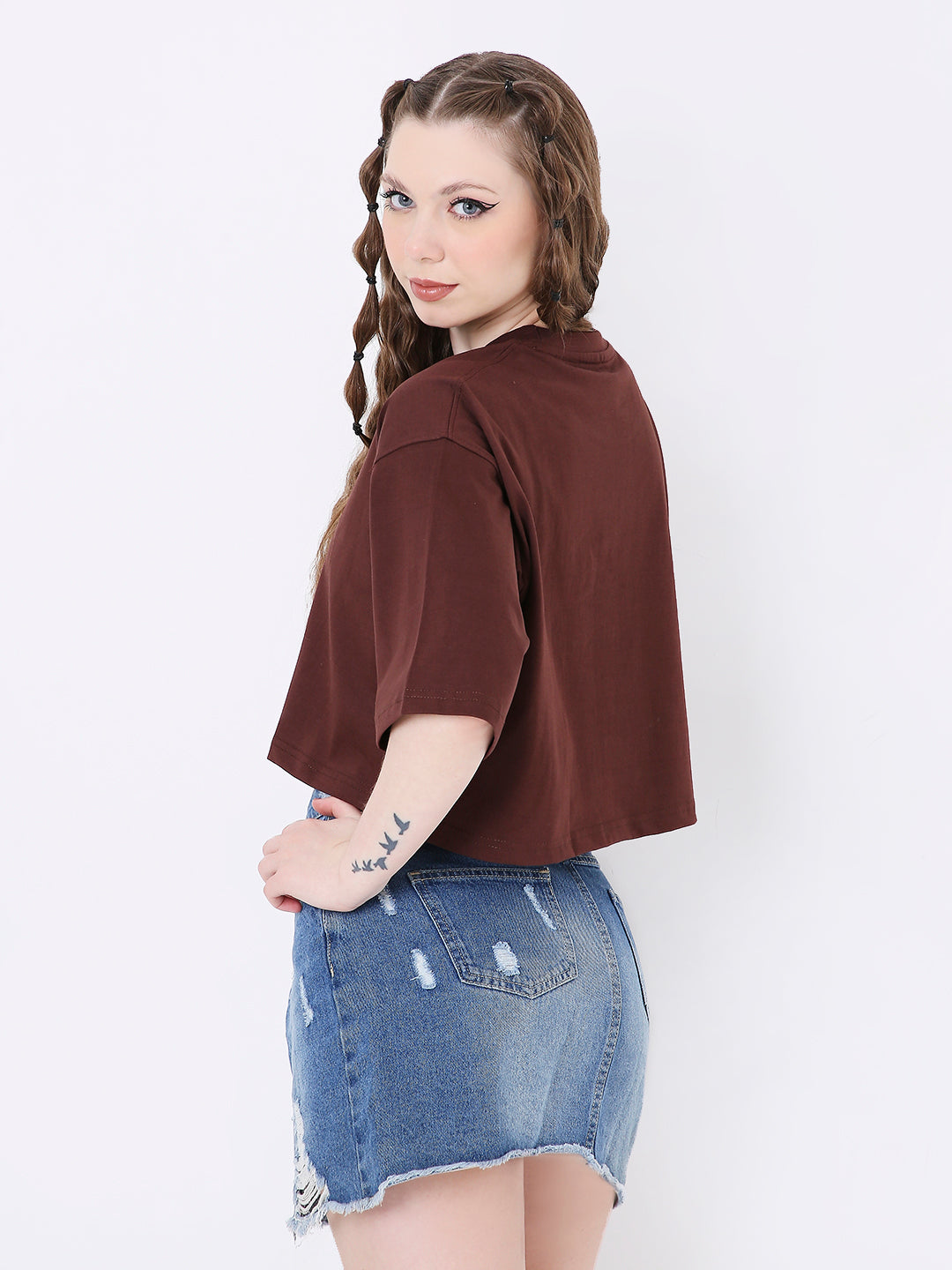 Oversize brown crop top with short sleeves worn with distressed blue denim skirt.