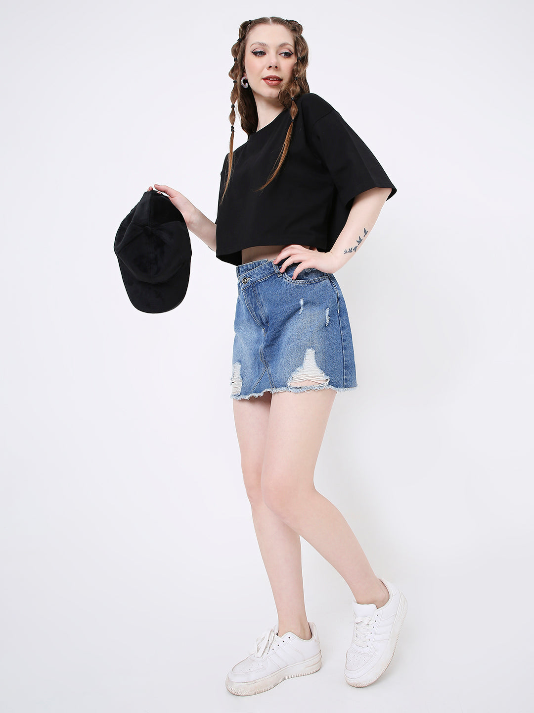 Oversize black solid crop top with short sleeves paired with distressed denim shorts and white sneakers.