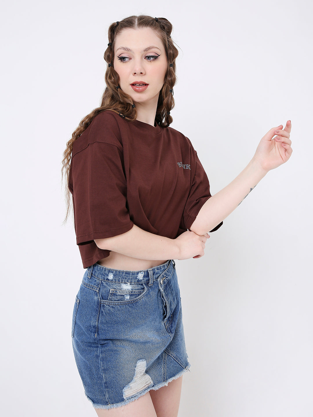 Oversize brown printed crop top with short sleeves paired with distressed denim skirt.