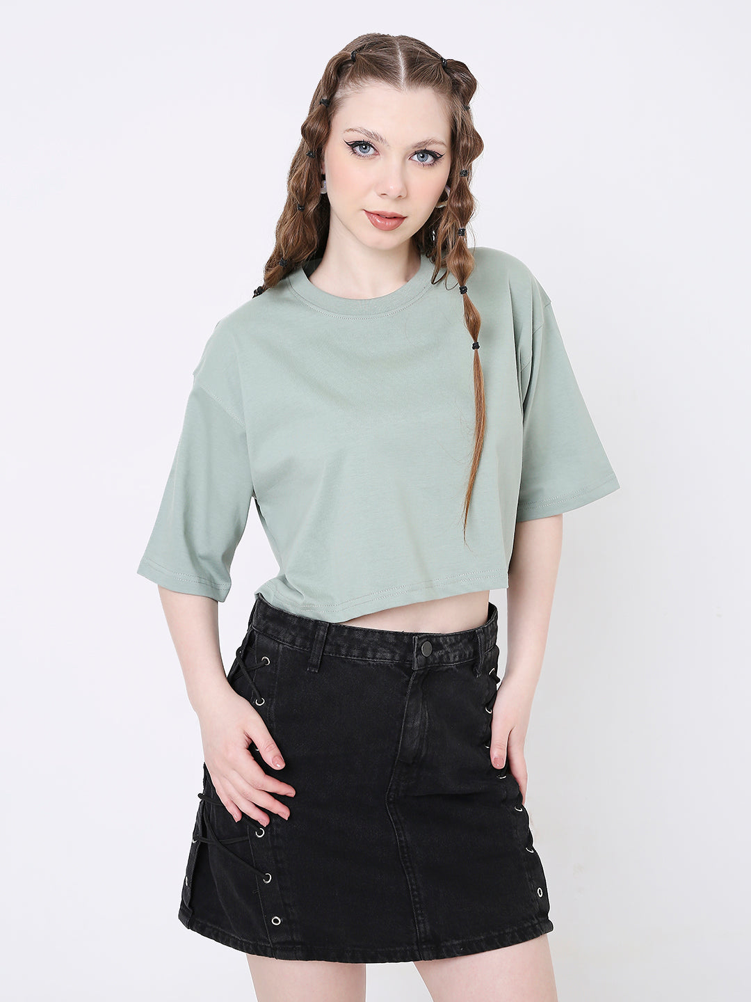 Oversize sage green crop top with short sleeves and round neck paired with a black denim skirt.