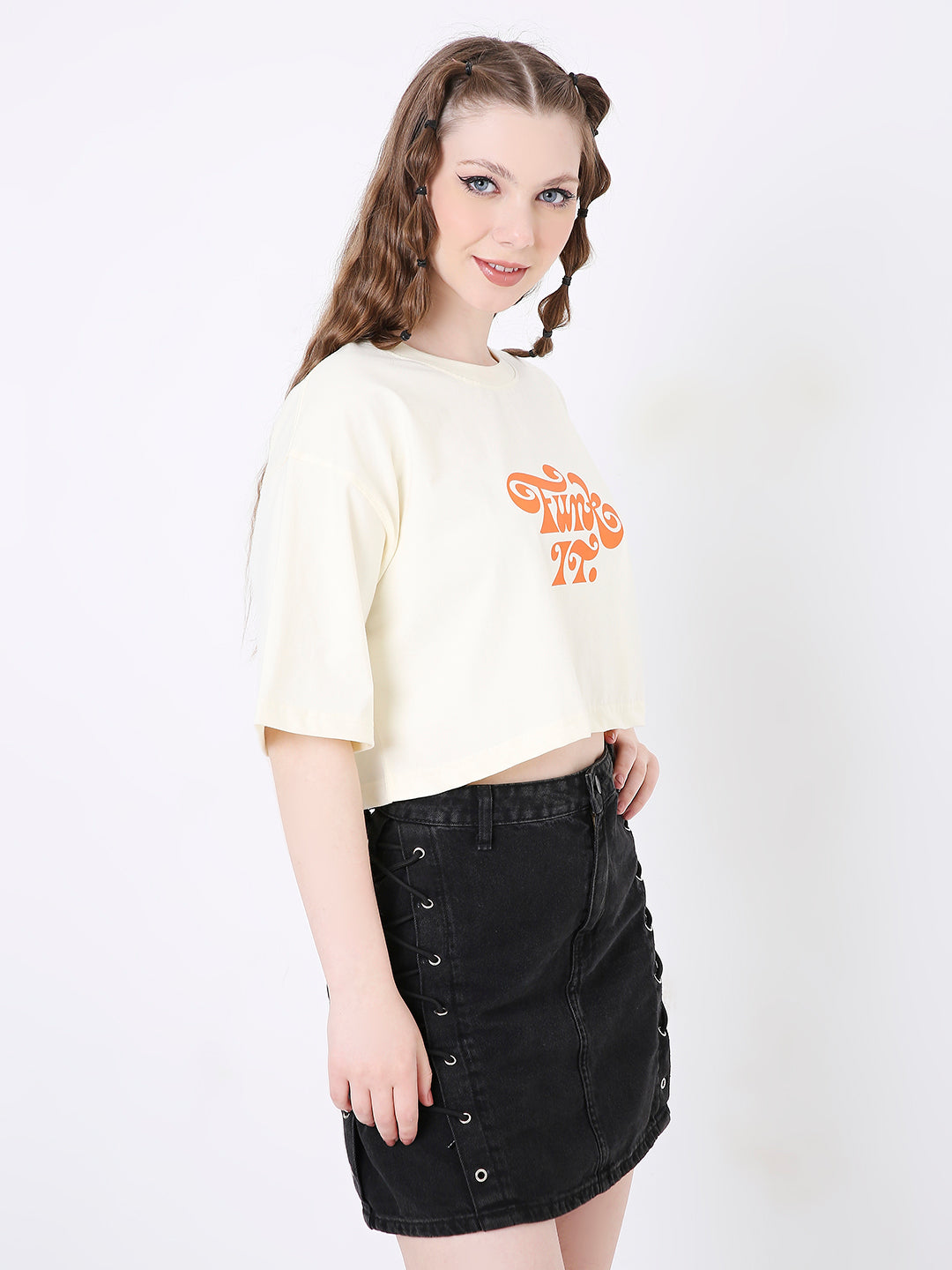 Off-white oversized cropped top with orange graphic print paired with black button-front skirt.