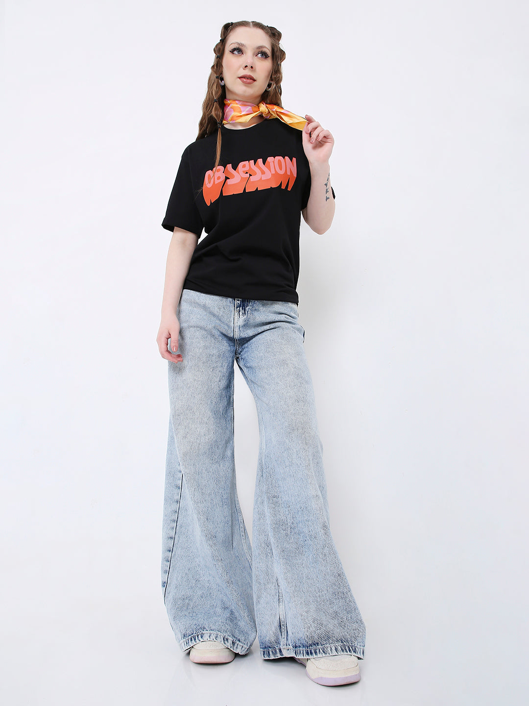 Black relaxed fit t-shirt with bold red and orange graphic print, paired with light blue wide-leg jeans.