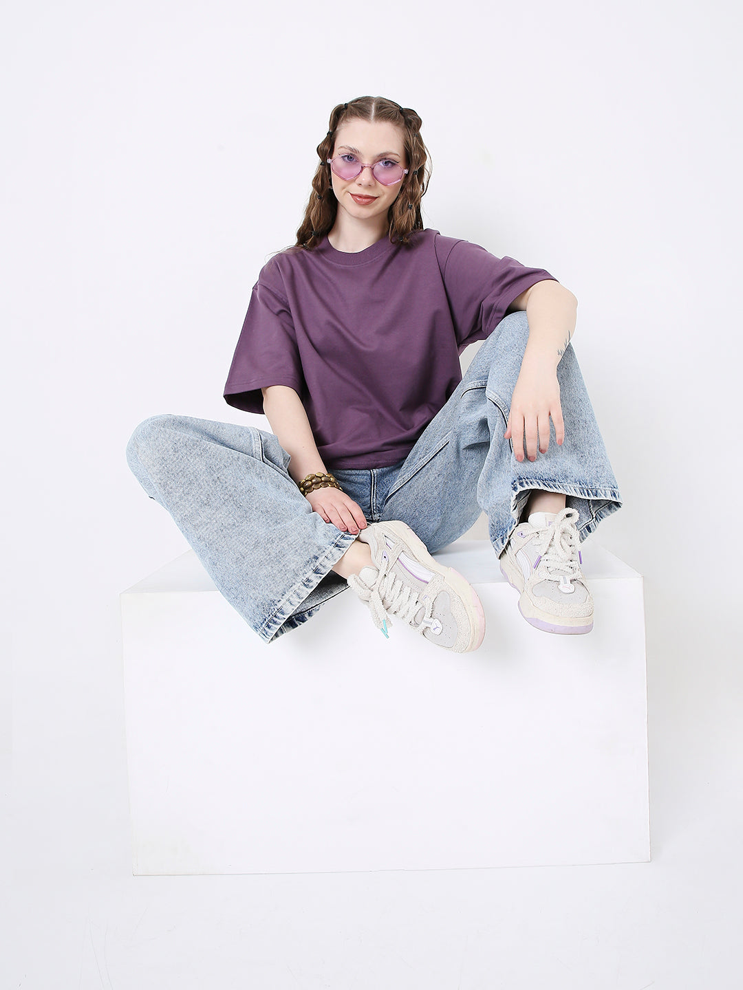 Oversize grape purple cotton T-shirt paired with light blue wide-leg jeans and white sneakers.