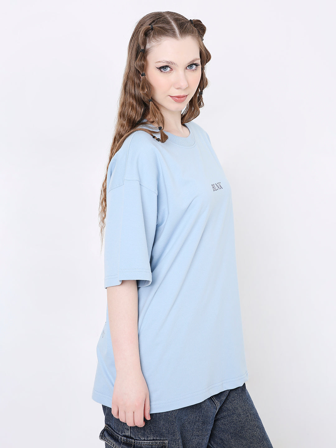 Oversize light blue t-shirt with small dark printed text on chest, worn with dark pants.