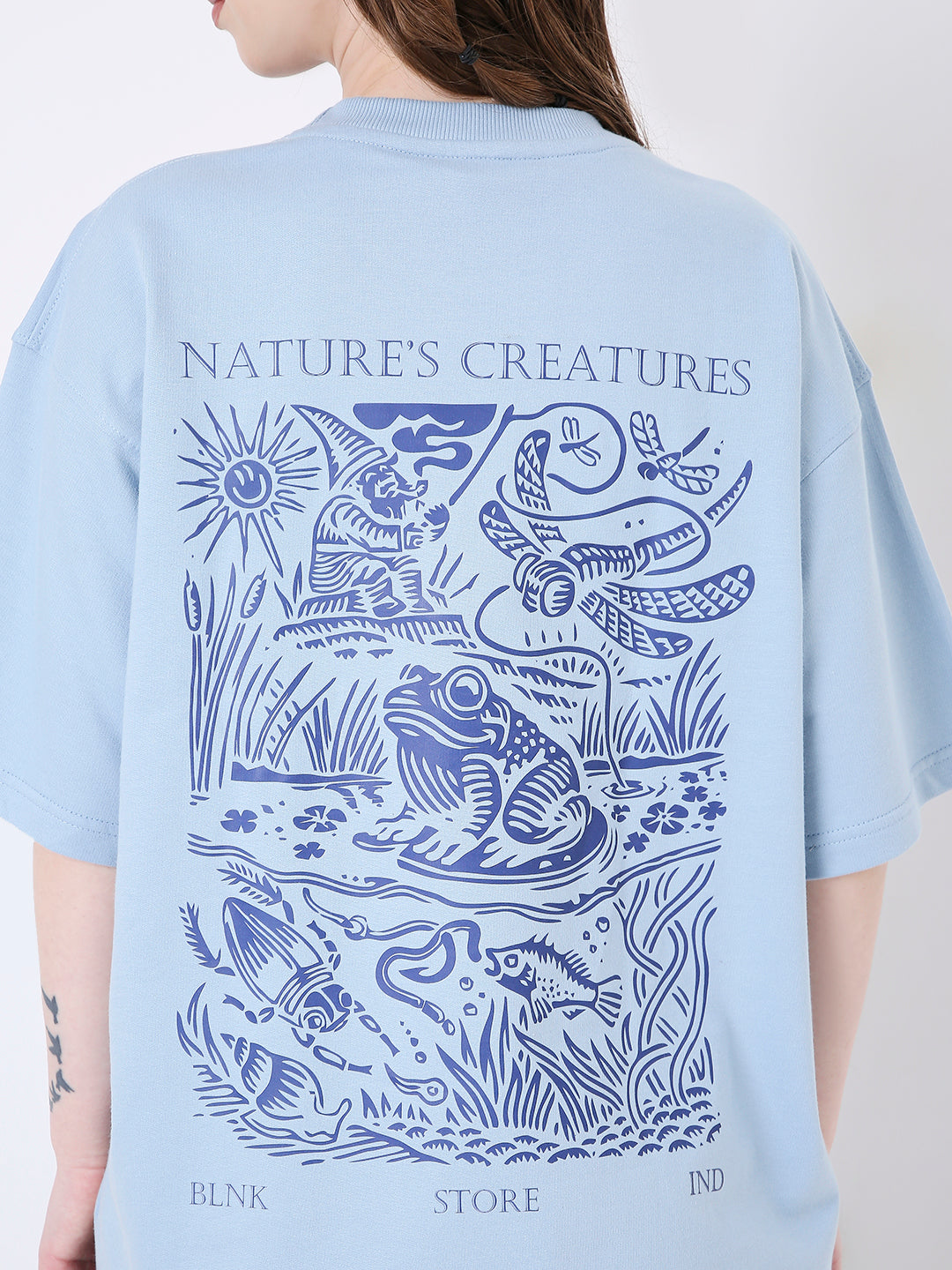 Light blue oversized t-shirt with dark blue nature-inspired graphic print on the back.