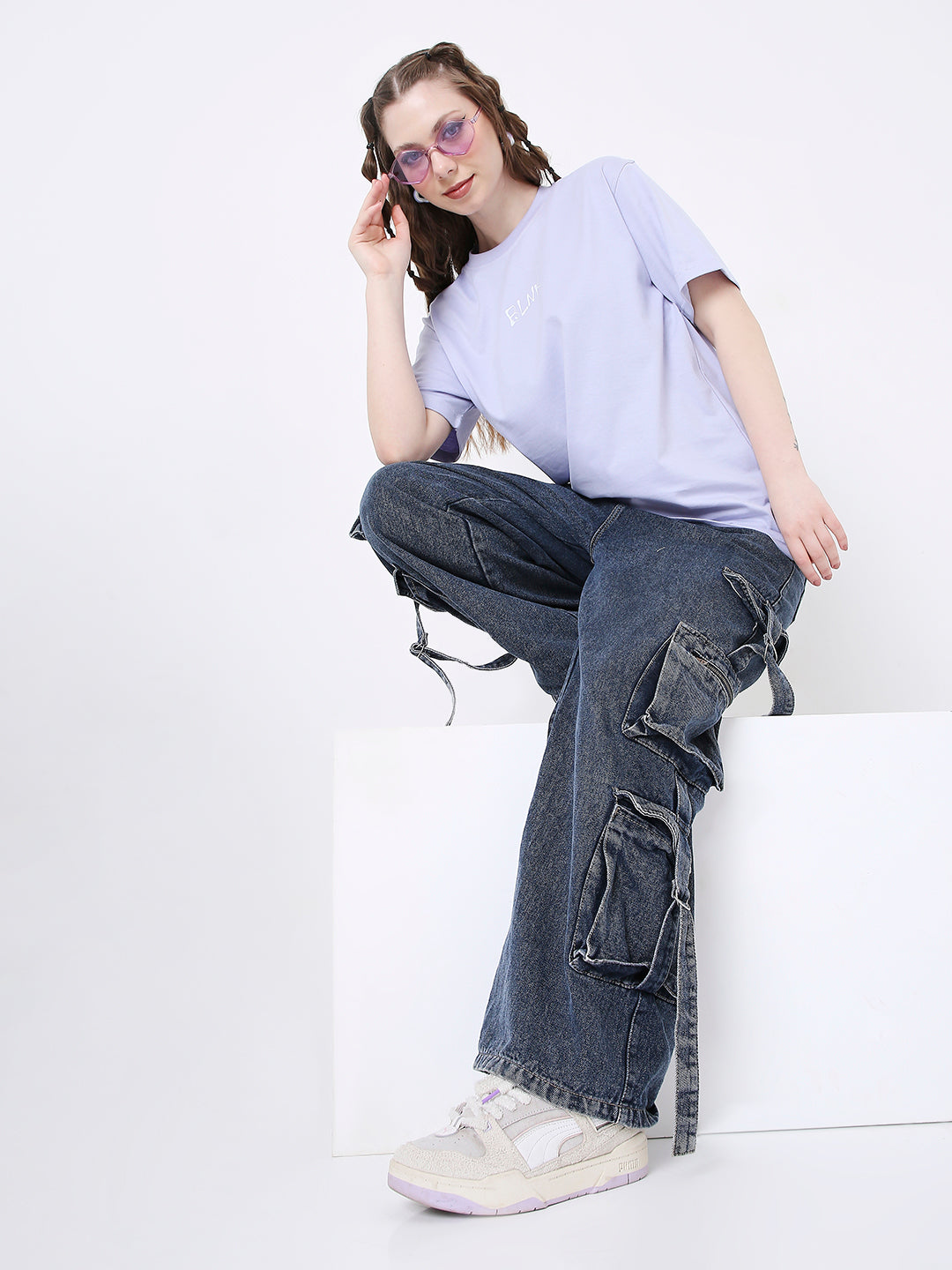 Lavender relaxed fit T-shirt with subtle white print, paired with dark blue cargo jeans and beige sneakers.