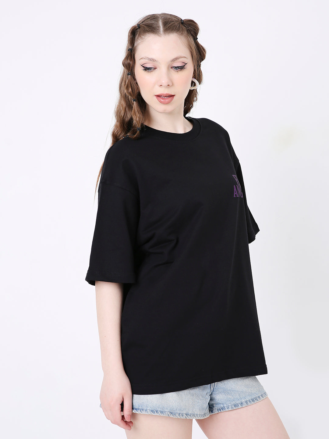 Oversized black t-shirt with a small purple graphic on the chest, paired with light denim shorts.