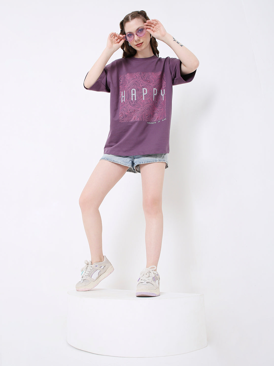 Oversize purple t-shirt with large white grape print, worn with light denim shorts and sneakers.
