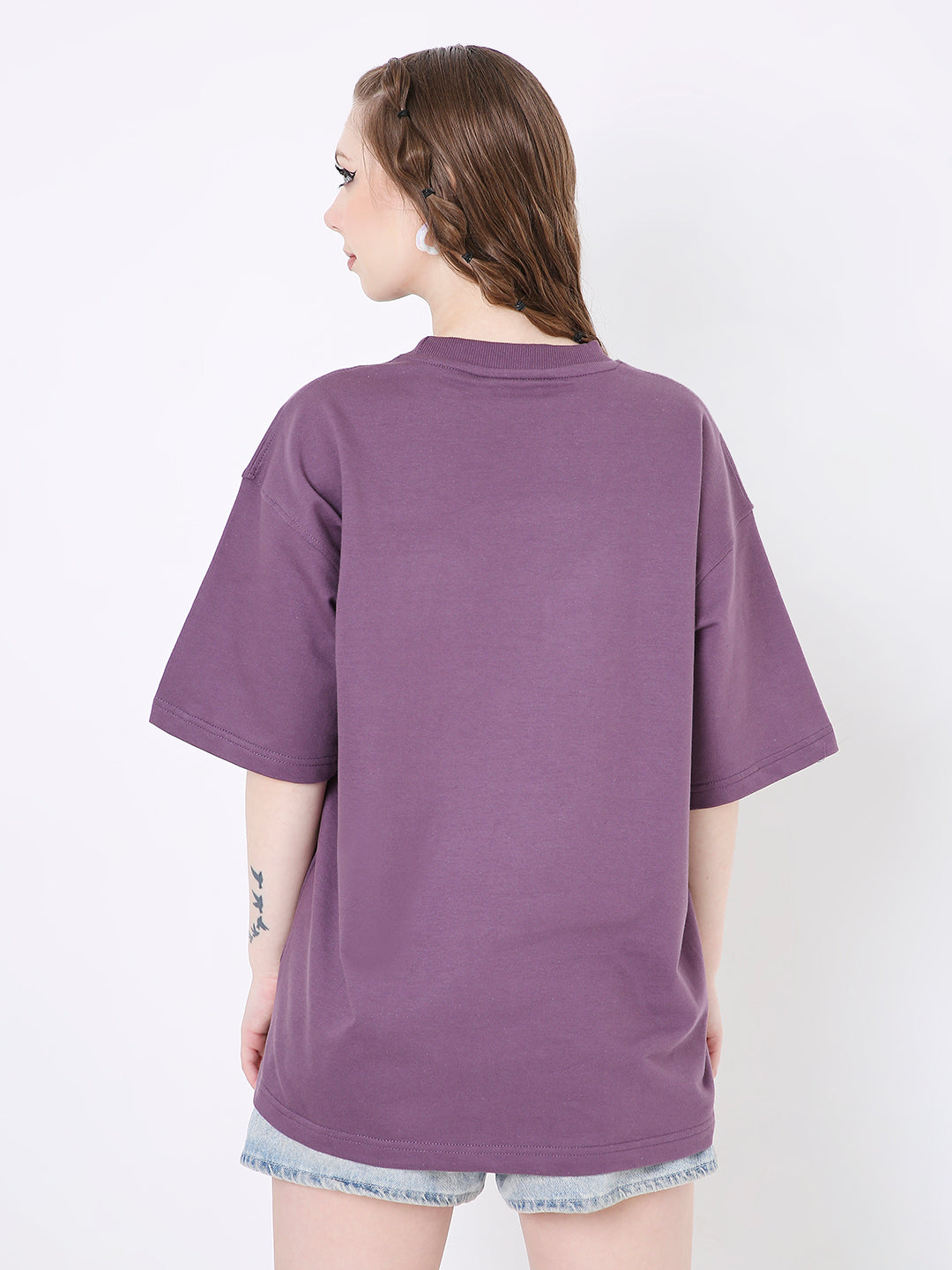 Purple oversized t-shirt with short sleeves and no visible print, worn with light denim shorts, back view.