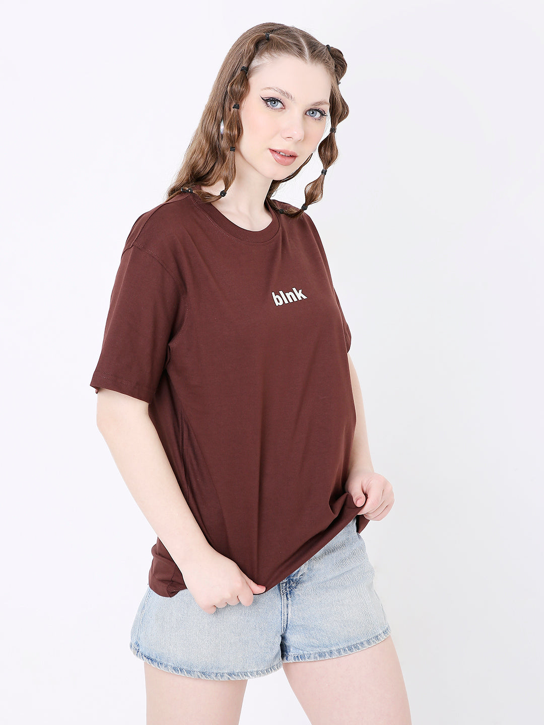 Brown relaxed fit t-shirt with small white text print on chest, paired with light denim shorts.